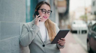 Young woman executive talking on the smartphone using touchpad at street