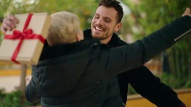 Anne ve oğul gülümsüyor. Parktaki doğum günü hediyesiyle kendine güvenen sürpriz.