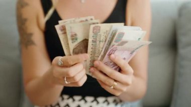 Evde Mısır banknotlarını sayan genç bir kadın.