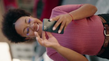 Afro-Amerikalı kadın sokakta akıllı telefon kullanarak kendine güveniyor.