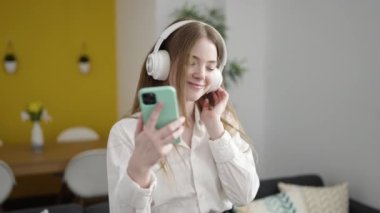 Evde müzik dinleyen ve dans eden genç sarışın kadın.