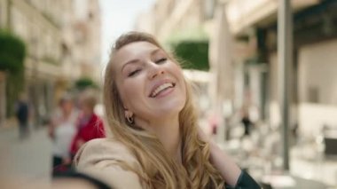 Genç sarışın kadın gülümsüyor. Kendine güveni tam. Kameranın önünde özçekim yapıyor.