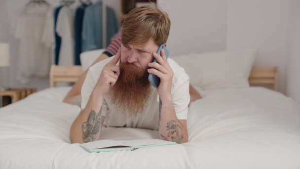Young Redhead Man Talking Smartphone Writing Book Bedroom — Stock Video