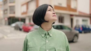 Sokakta rahat bir ifadeyle gökyüzüne bakan genç Çinli kadın.