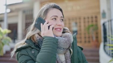 Genç sarışın kadın gülümsüyor. Kendine güveni tam. Akıllı telefondan konuşuyor.