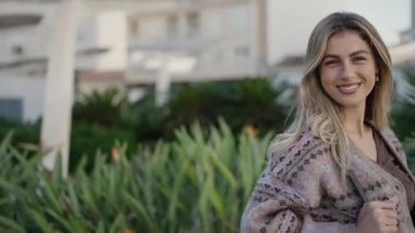 Parkta kendine güvenen, gülümseyen sarışın genç bir kadın.