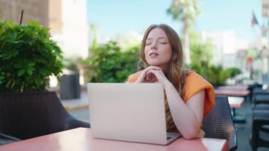 Young woman stressed using laptop sitting on table at coffee shop terrace