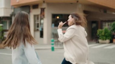 Anne ve kız gülümseyerek sokakta dans ediyorlar.