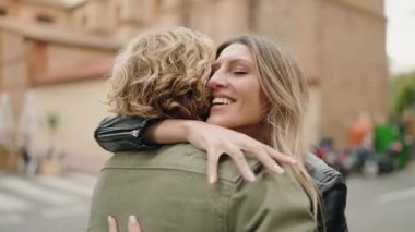 Young caucasian couple smiling confident hugging each other standing at street