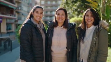 Anne ve kızları parkta öpüşüp sarılıyorlar.