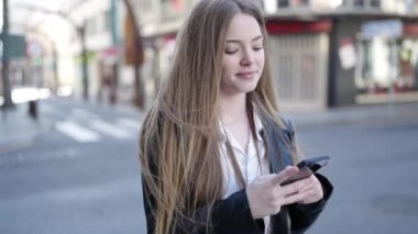 Sokakta akıllı telefon kullanan, kendine güvenen genç sarışın kadın.