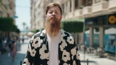 Young redhead man standing with arms crossed gesture at street