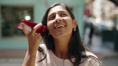 Genç ve güzel İspanyol kadın gülümsüyor. Caddedeki akıllı telefondan kendine güvenen bir sesli mesaj dinliyor.