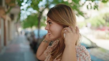 Sokakta müzik dinlerken kendinden emin gülümseyen genç bir kadın.