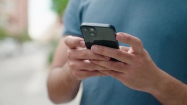 Sokakta akıllı telefon kullanan genç bir latin.