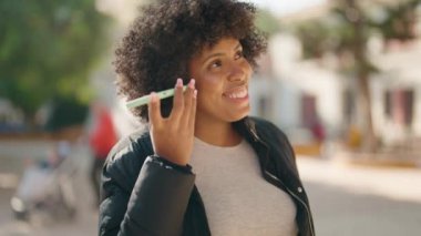 Genç Afrikalı Amerikalı kadın gülümsüyor. Parktaki akıllı telefondan kendine güvenen sesli mesaj dinliyor.