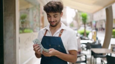 Genç Arap garson lokantada çalışarak dolarları sayıyor.