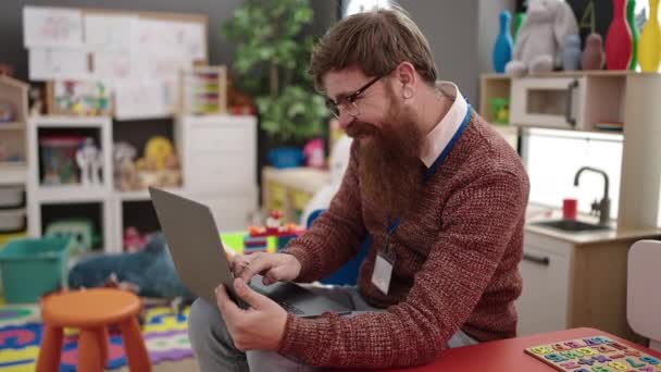 Young Redhead Man Preschool Teacher Using Laptop Sitting Chair Kindergarten — 图库视频影像