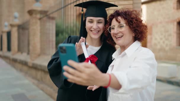 2人の女性母親と娘が大学でビデオ通話を持っている卒業証書を持っています — ストック動画