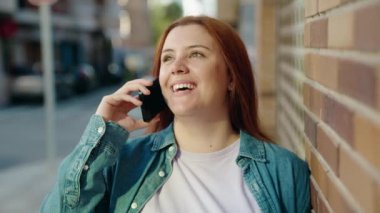 Young beautiful plus size woman smiling confident talking on the smartphone at street
