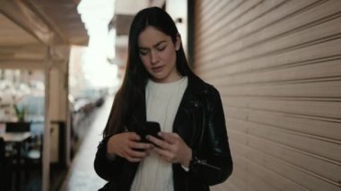 Sokakta akıllı telefon kullanan, kendine güvenen genç İspanyol kadın.