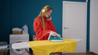 Çamaşır odasında müzik dinleyen genç sarışın kadın.