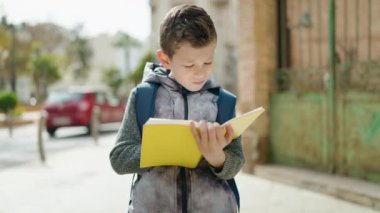 Blond child student hugging book standing at street