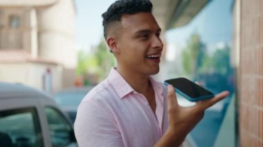 Genç Latin adam gülümsüyor. Kendine güveniyor. Akıllı telefondan konuşuyor.