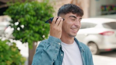 Genç İspanyol adam gülümsüyor. Caddedeki akıllı telefondan kendine güvenen bir sesli mesaj dinliyor.