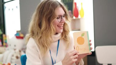 Young blonde woman preschool teacher having vocabulary lesson at kindergarten