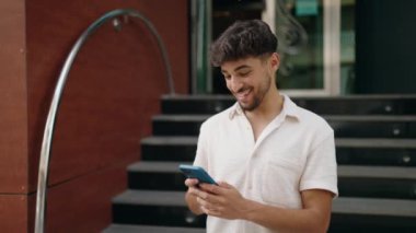 Young arab man smiling confident having video call at street