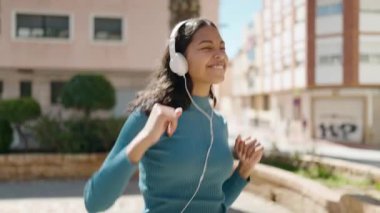 Genç Afrikalı Amerikalı kadın müzik dinliyor ve sokakta dans ediyor.