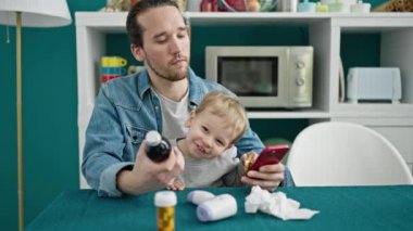 Baba ve oğul yemek odasında akıllı telefon kullanıyor.