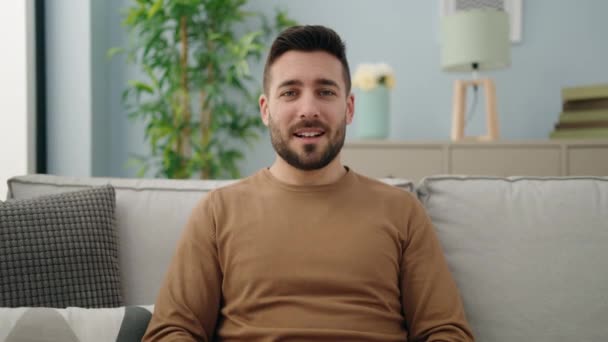 Молодий Іспаномовний Чоловік Сидить Дивані Розмовляючи Вдома — стокове відео