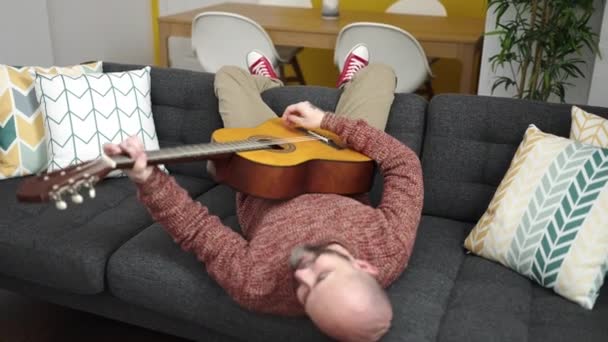 Genç Kel Adam Evdeki Kanepede Uzanmış Klasik Gitar Çalıyor — Stok video
