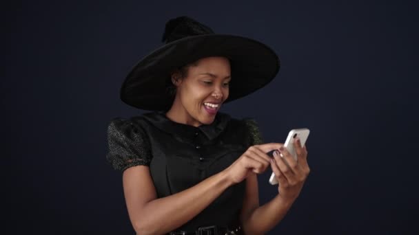 African American Woman Wearing Witch Costume Using Smartphone Isolated Black — Stock video