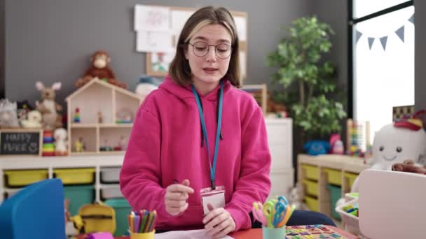 Junge Blonde Kindergärtnerin Schreibt Kindergarten Dokument — Stockvideo