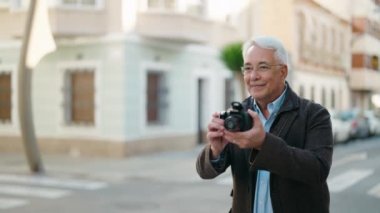 Orta yaşlı çift sokakta profesyonel kamera kullanarak fotoğraf çekiyor.