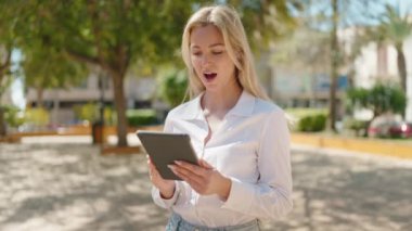 Parkta dokunmatik ped kullanan kendine güvenen genç sarışın kadın.