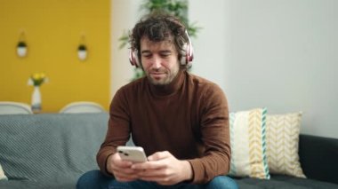 Genç İspanyol adam evde müzik dinliyor ve dans ediyor.