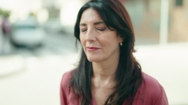 Orta yaşlı İspanyol kadın sokakta kendine güvenerek gülümsüyor.