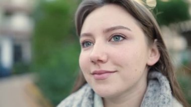 Genç sarışın kadın parkta rahat bir ifadeyle yan tarafa bakıyor.