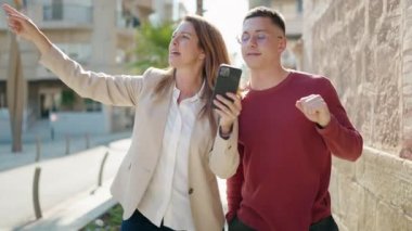 Erkek ve kadın, anne ve oğul, caddede yürürken GPS akıllı telefonu kullanıyor.