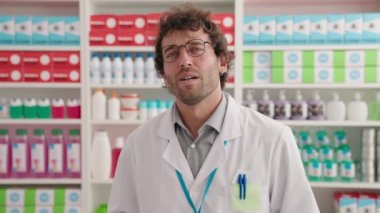 Young hispanic man pharmacist speaking at pharmacy