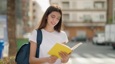 Genç İspanyol kız güler yüzlü Sokakta kendine güvenen kitap okuyan
