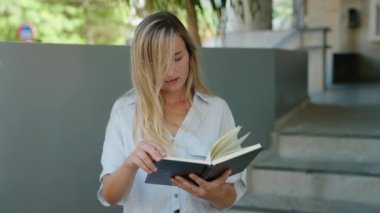 Sokakta kitap okuyan genç sarışın kadın.