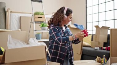 Orta yaşlı İspanyol kadın yeni evinde eşyalarını yerleştirirken müzik dinliyor.