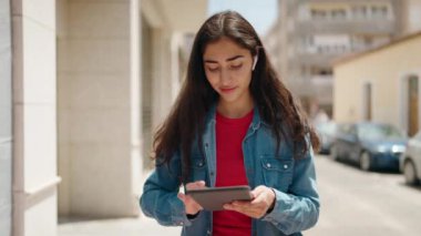 Young hispanic girl smiling confident using touchpad at street