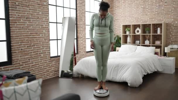 Mujer Afroamericana Sonriendo Confiada Midiendo Peso Usando Máquina Pesaje Dormitorio — Vídeo de stock