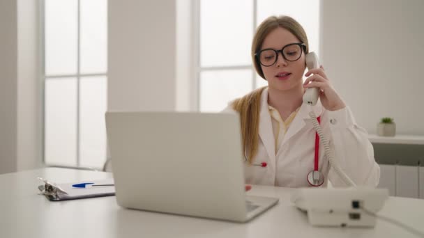 Mujer Rubia Joven Vistiendo Uniforme Médico Hablando Por Teléfono Clínica — Vídeo de stock
